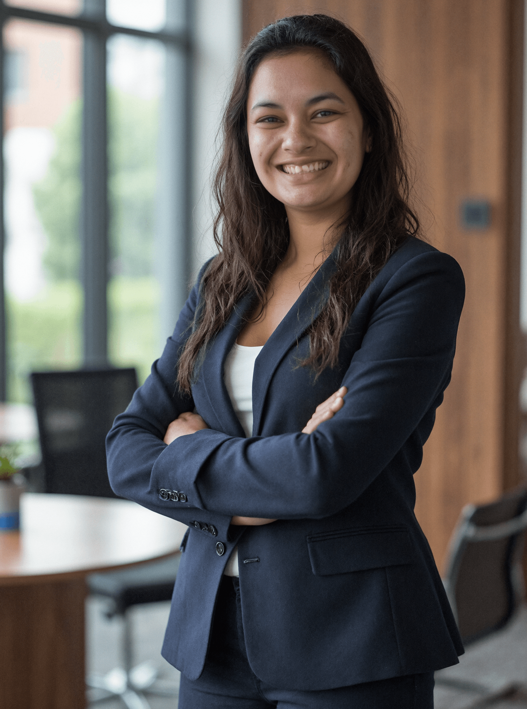 Me wearing a dark blazer crossing my arms in front of a modern office